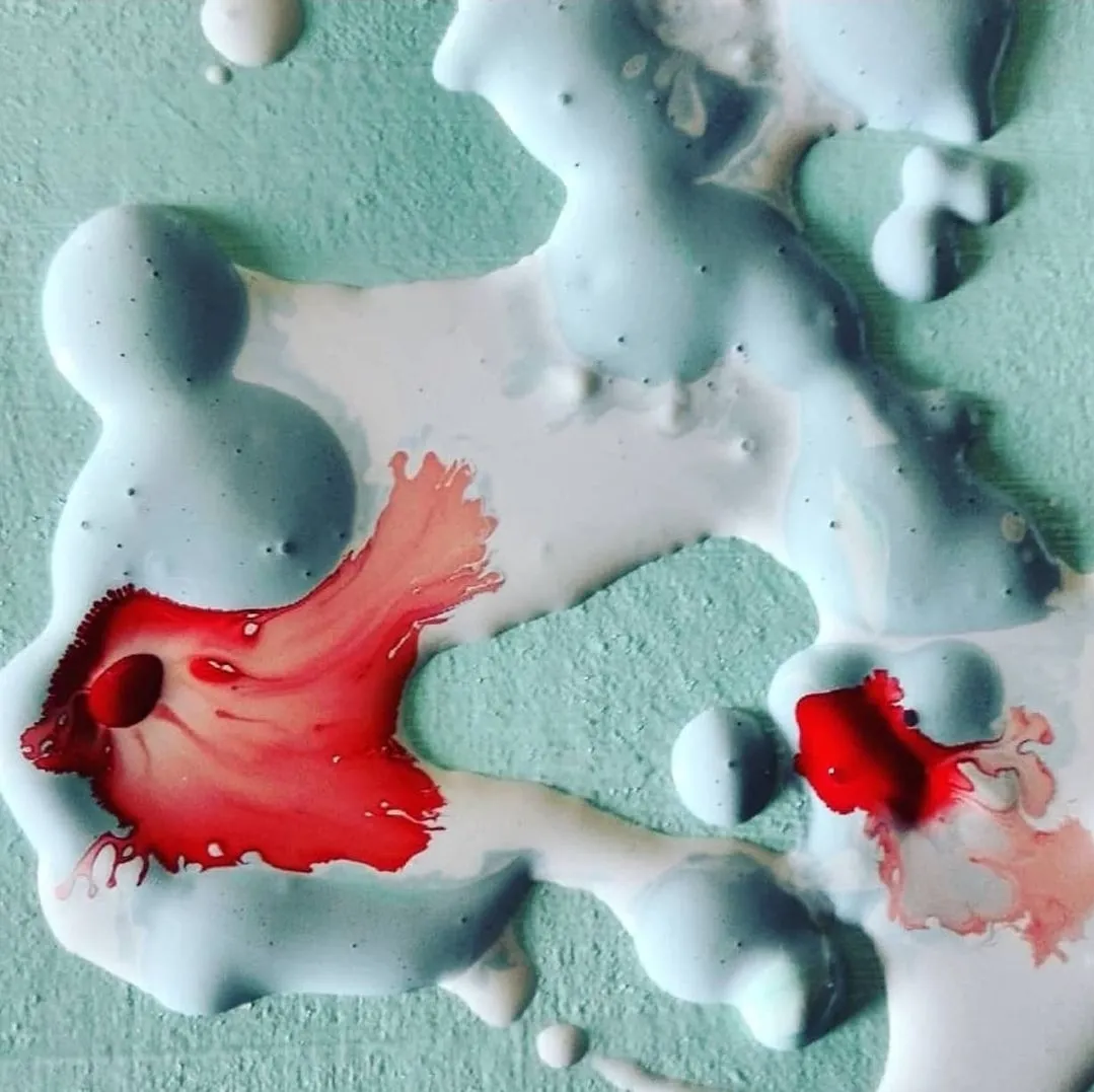 Dipinto astratto: colate di colore bianco-azzurro con macchie rosse su fondo verde acqua.